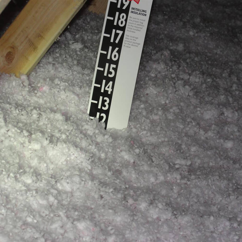 image of ruler in insulation measuring how deep the insulation is