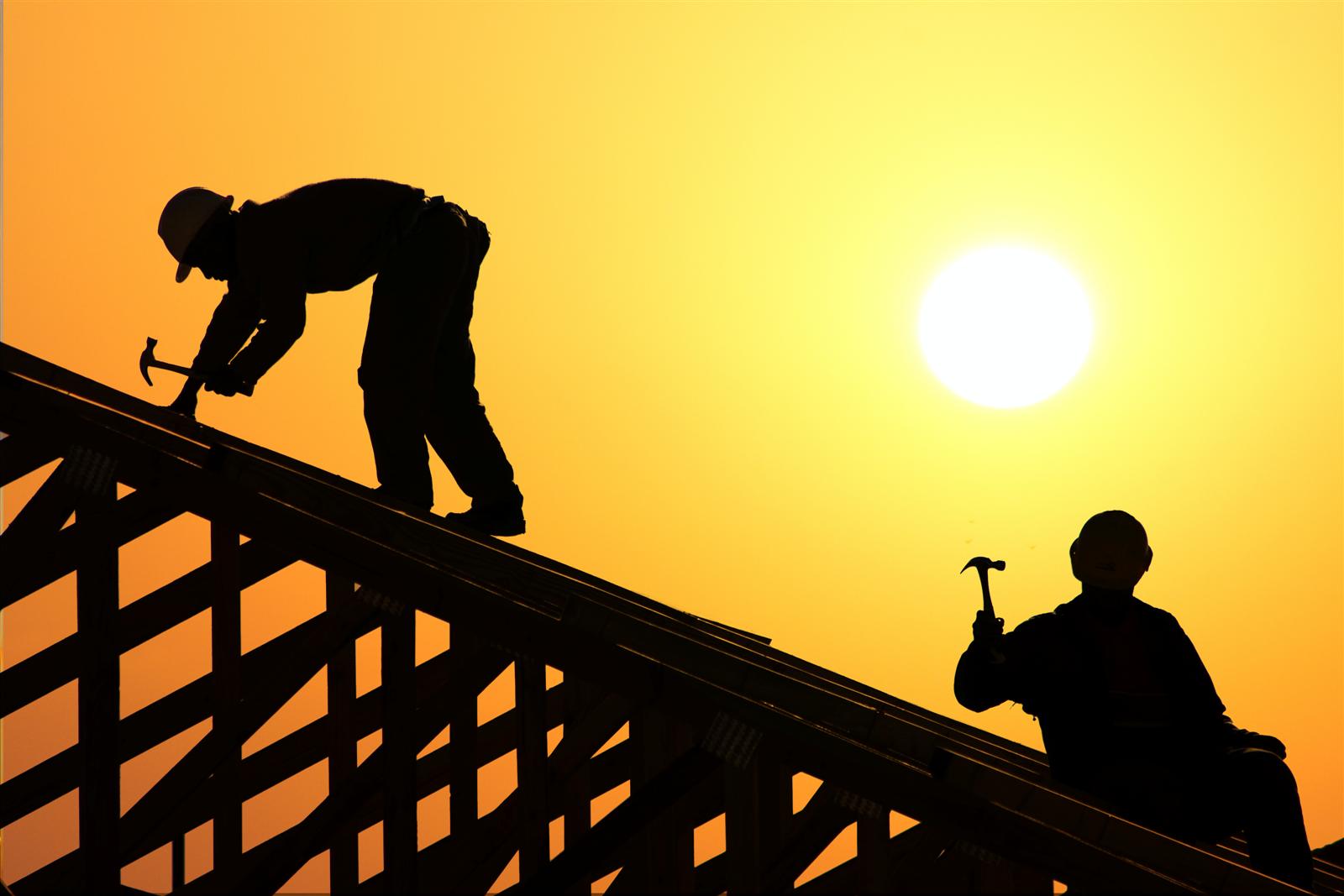 image of two roofers on top of roof with sun setting