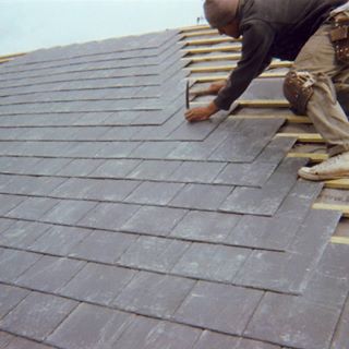 image of man on roof putting shingles down